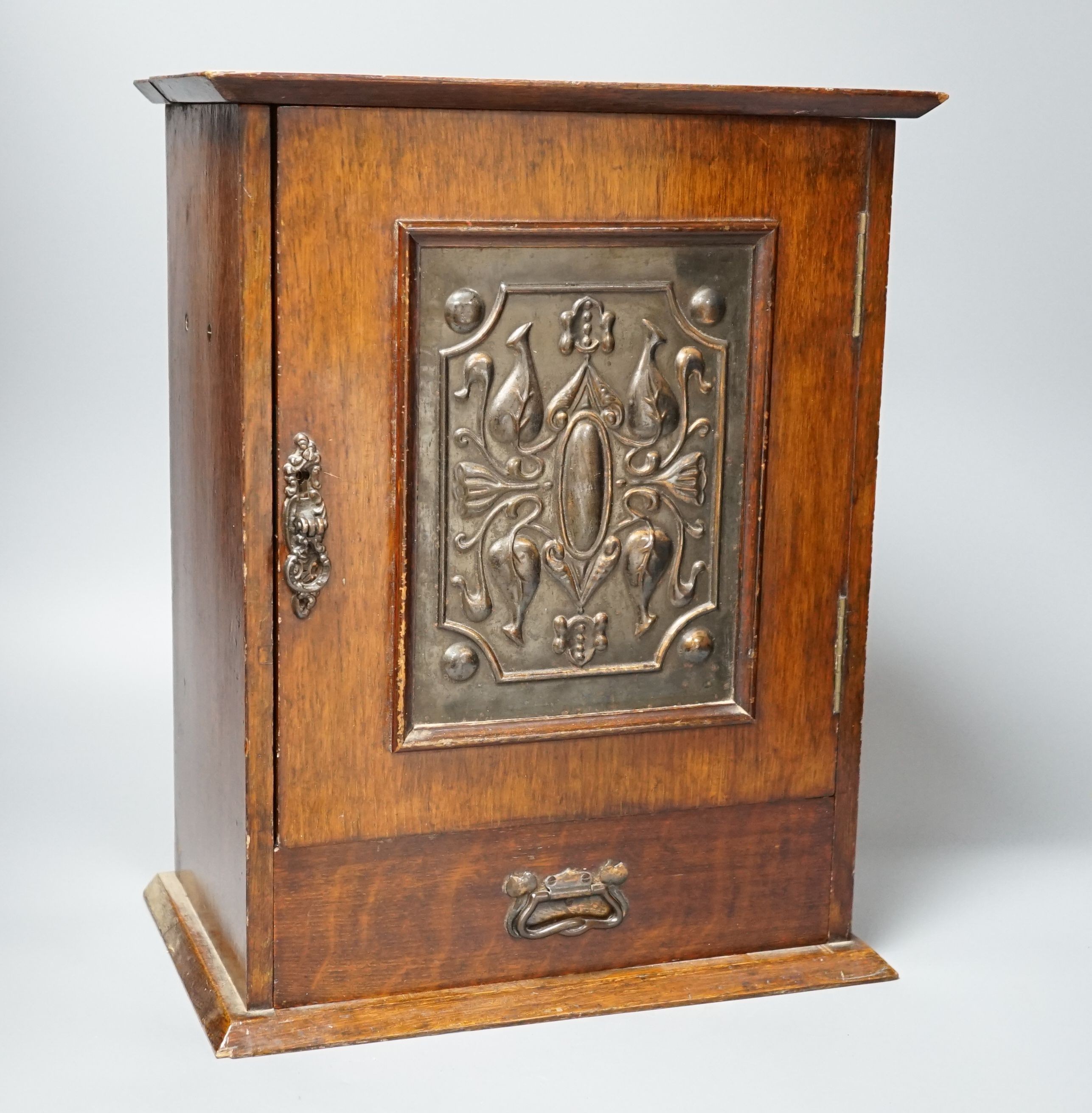 A late Victorian smokers cabinet with embossed metal panel to door and fitted interior 40cm